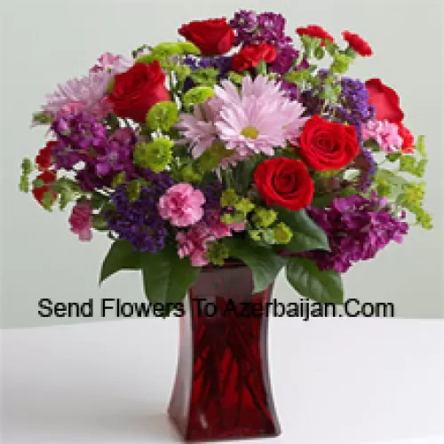Roses rouges, oeillets roses et autres fleurs saisonnières assorties dans un vase en verre